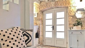 A room with a stone wall, a white door with glass panels, a white cabinet, and a bench with polka dot cushions. - Villa Alisia, Wunderschönes Natursteinhaus mit Pool bei Pore? (Vizinada)