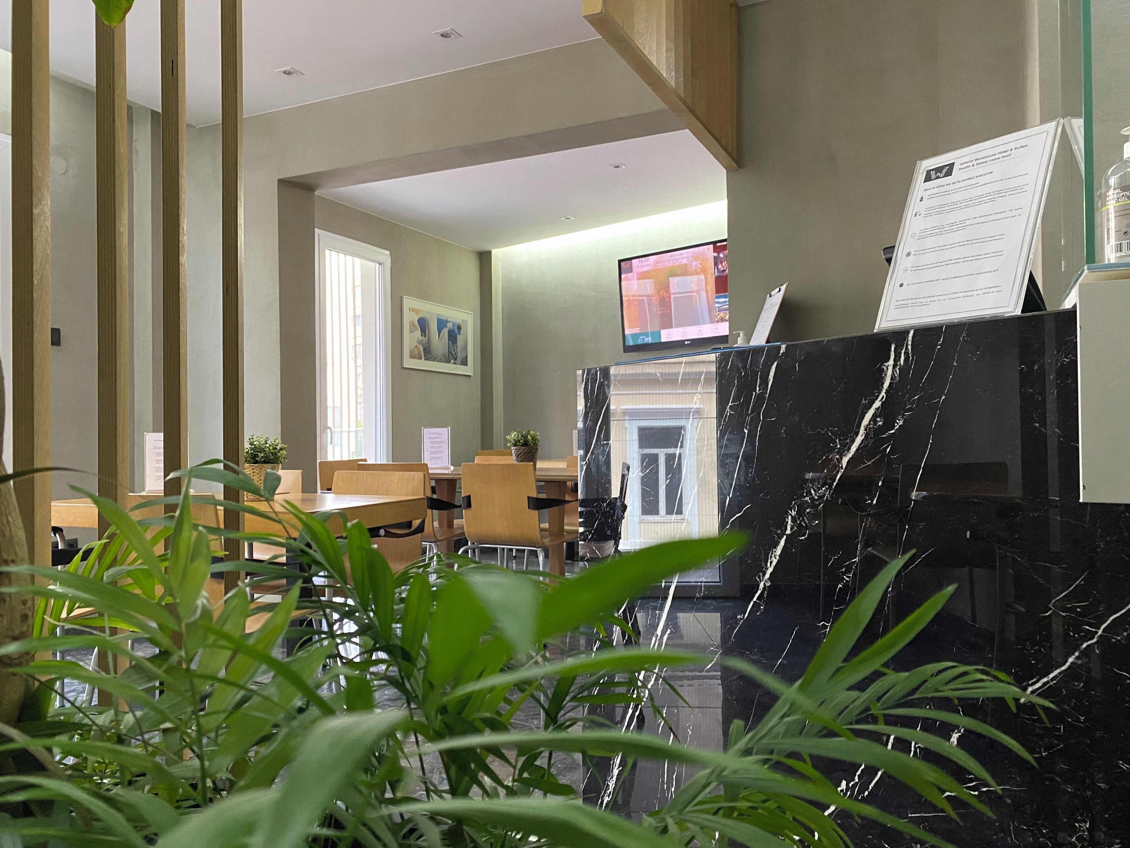 A hotel lobby with wooden paneling, a reception desk, a television, and a marble counter.