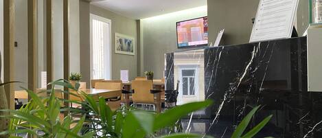 A hotel lobby with wooden paneling, a reception desk, a television, and a marble counter.