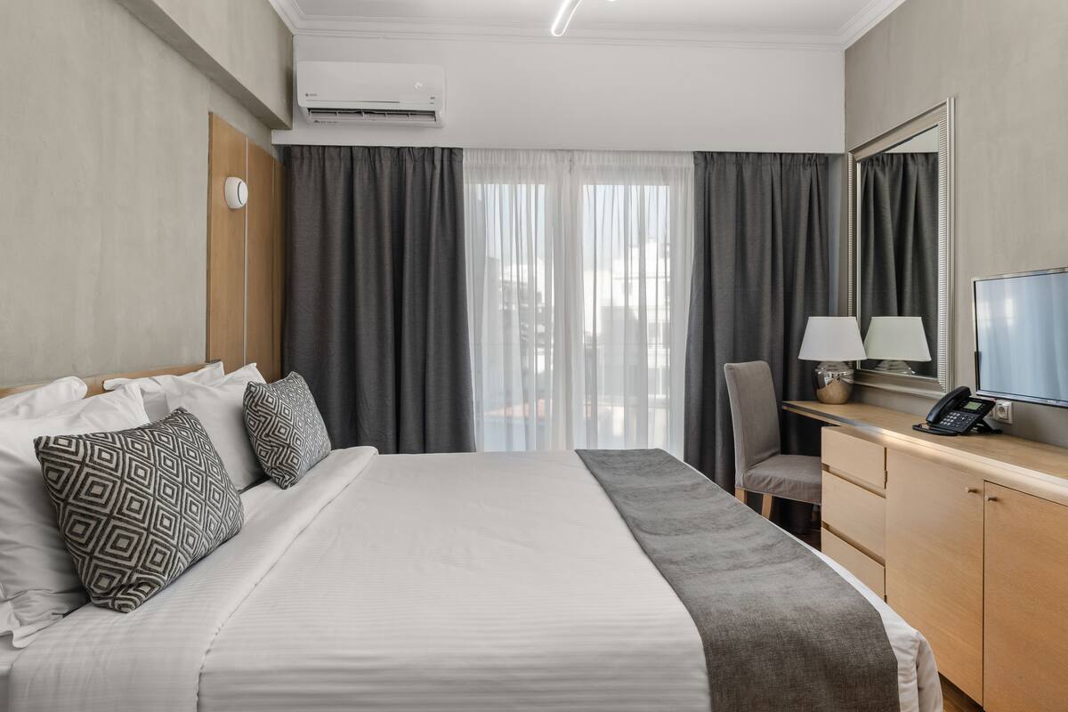 Une chambre d’hôtel avec un lit, un bureau avec une lampe, un téléphone et une télévision.
