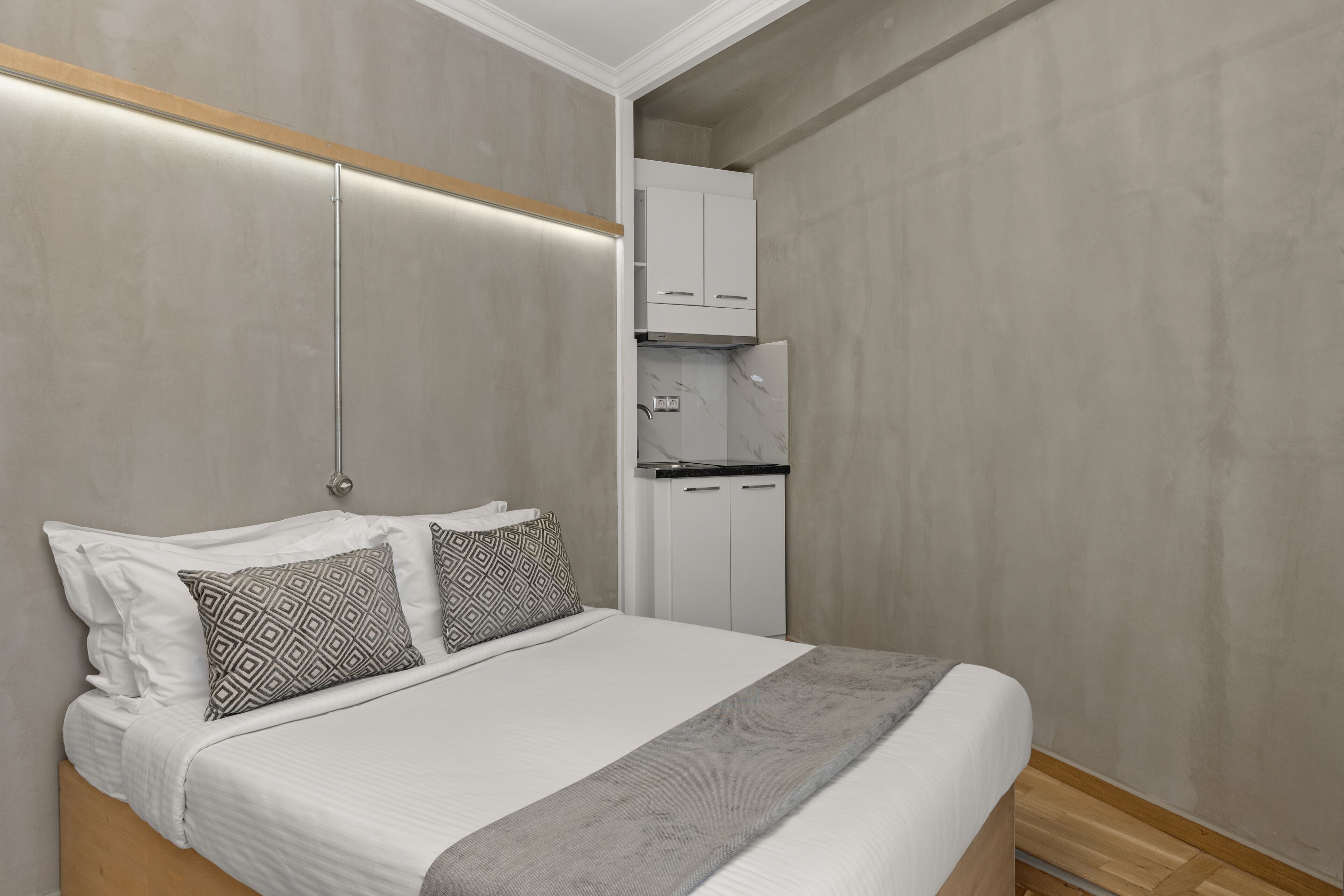 A modern bedroom with a bed, patterned pillows, a bedside table, and a built-in wardrobe.