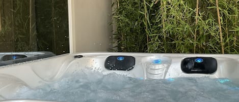 A hot tub with ice, surrounded by bamboo plants.