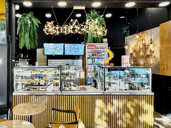 A bakery counter with pastries, a Coca-Cola refrigerator, and a wooden counter. - Athens Warehouse Boutique Hotel & Suites (Athens)