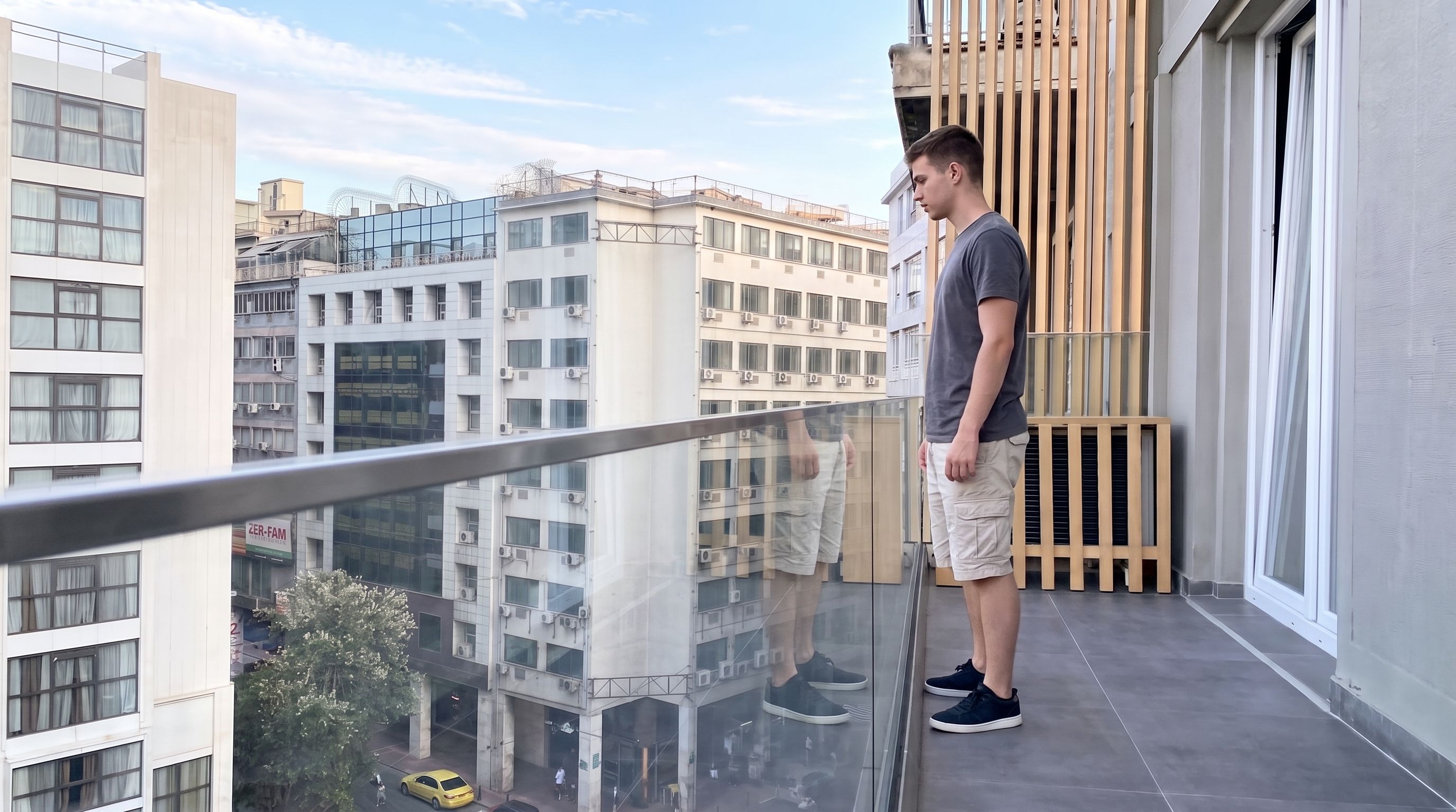 Un homme se tient sur un balcon, d’où l’on peut admirer les bâtiments environnants.