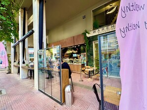 A storefront with a sign reading 'WAREHOUSE Boutique,' a glass partition, and a metal trash can.