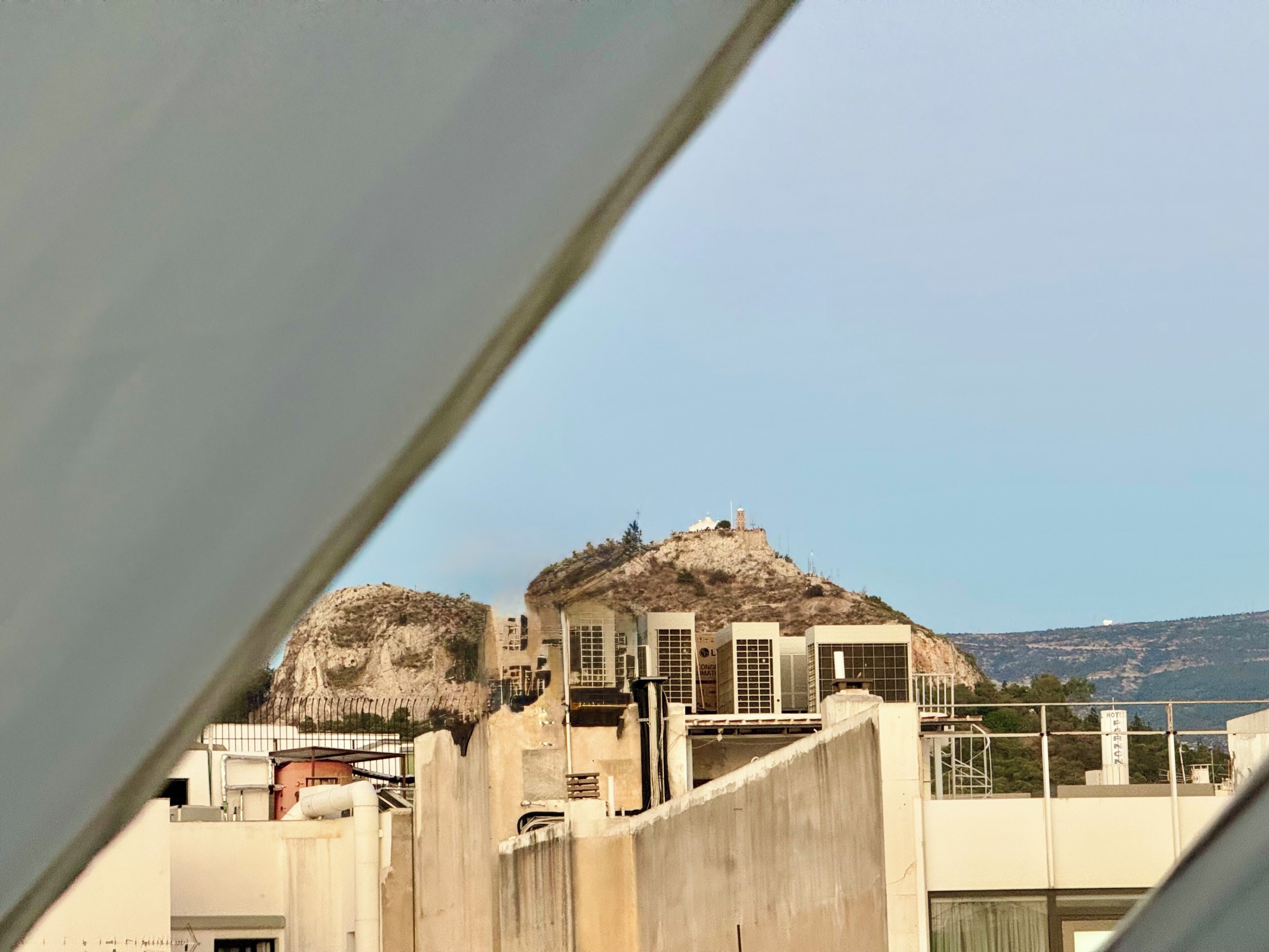 A hotel with a flat roof, air conditioning units, and a view of the surrounding landscape.