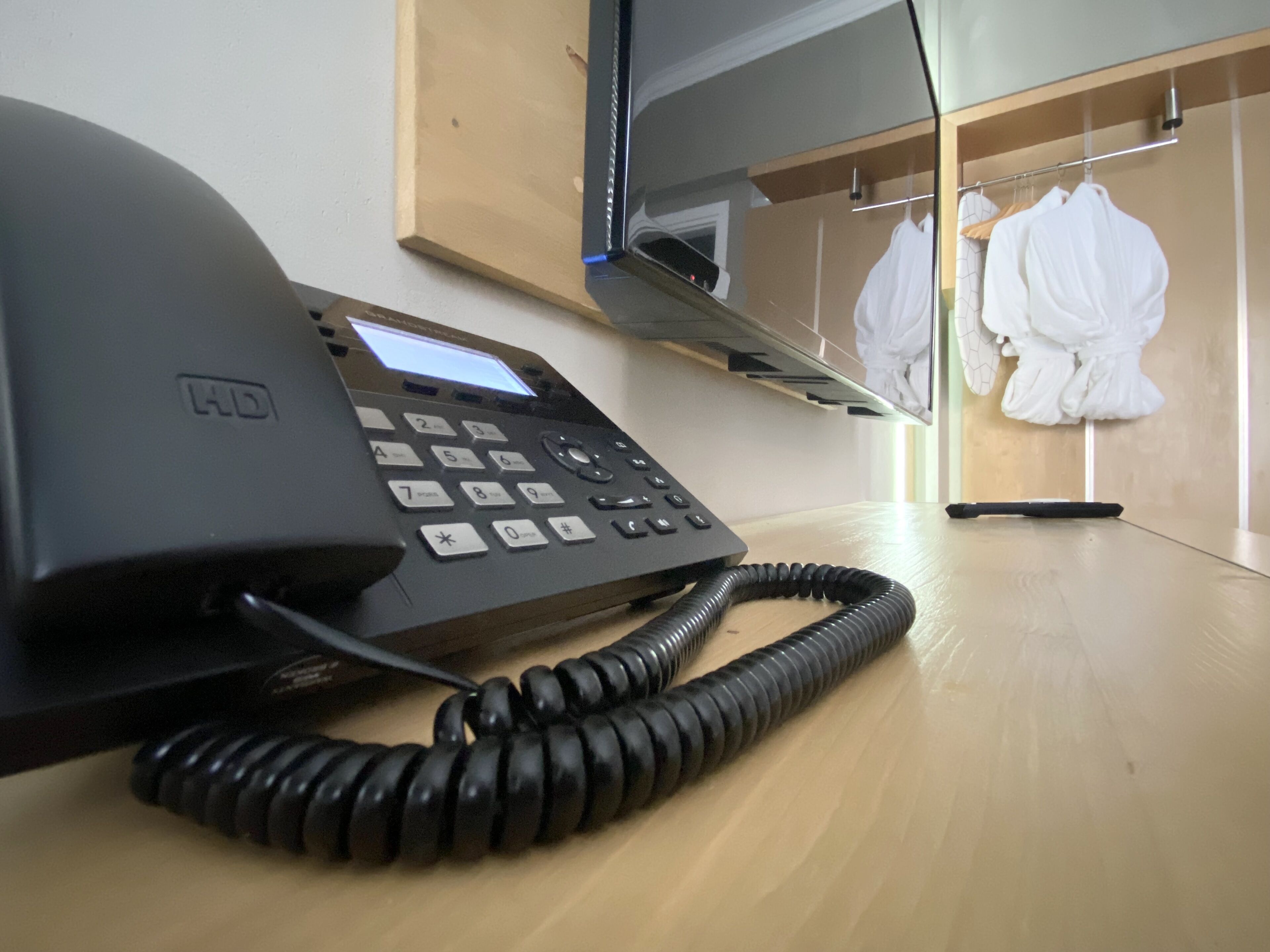 Ein schwarzes HD-Smartphone auf einem Holztisch mit einem aufgerollten Kabel.