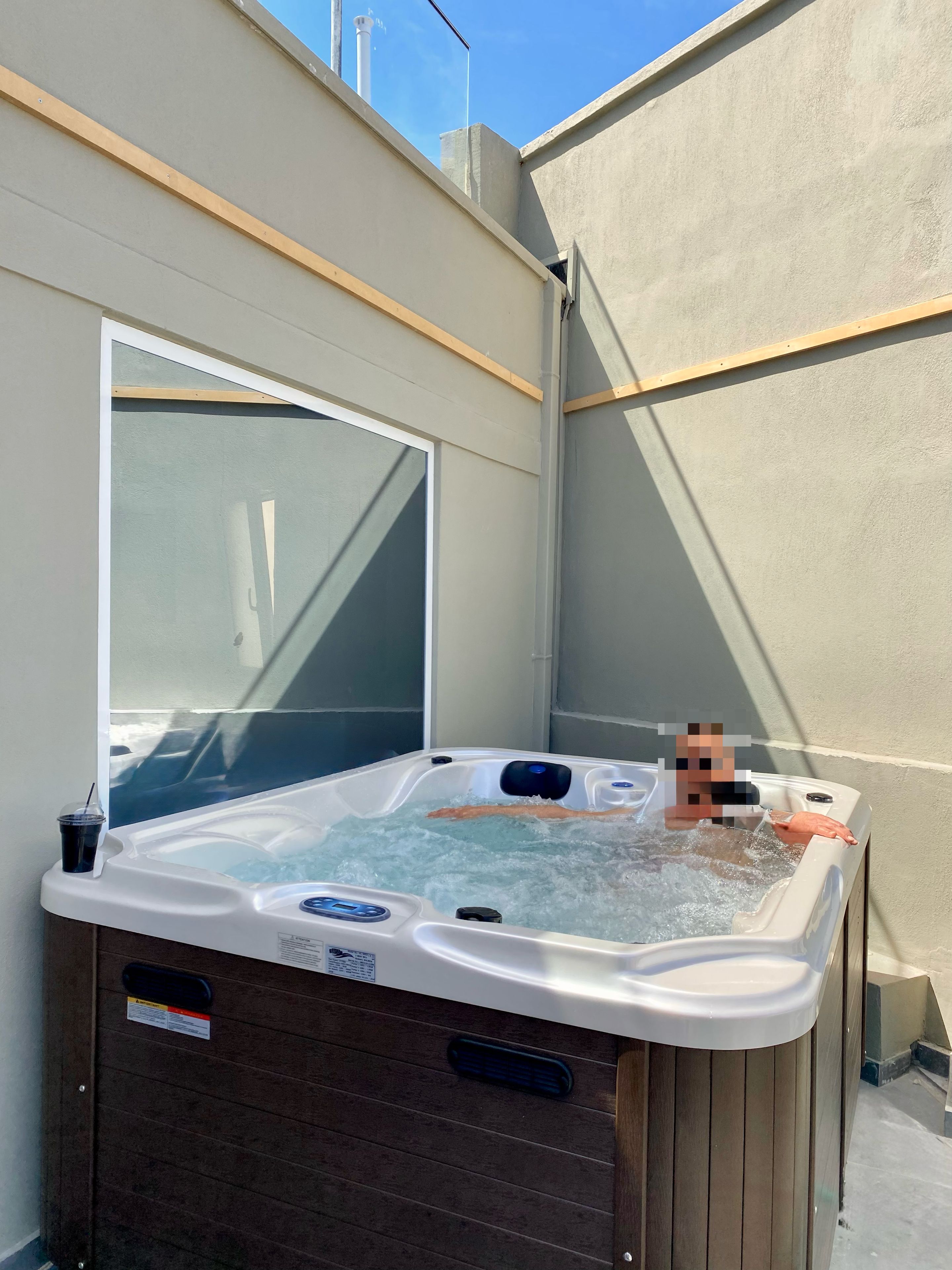 Un bain à remous avec une structure en bois, un panneau de commande et un porte-gobelet sur le côté.