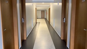 En moderne hotelgang med trædøre nummereret 112 og 109, der fører til værelser.
