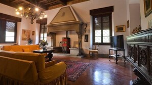 A spacious living room with a high ceiling, a chandelier, a fireplace, and a television.