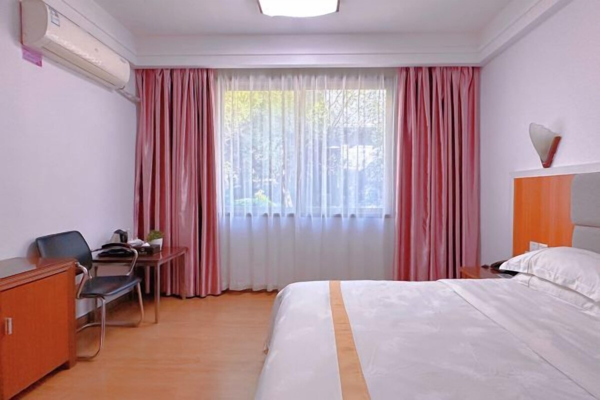 Ein Hotelzimmer mit Bett, Schreibtisch, Stuhl und Kleiderschrank.