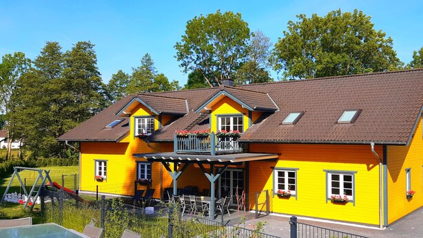 Un bâtiment jaune doté d’un balcon, de fenêtres et d’un garage.