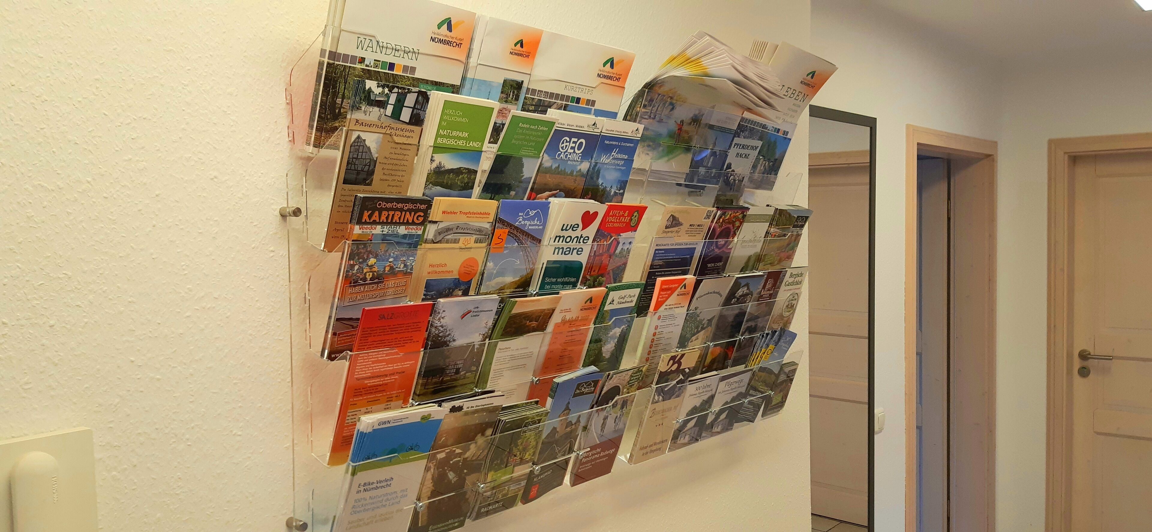 Um mural com um painel de avisos exibindo diversos folhetos de viagens e mapas.