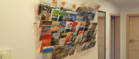 Un mur sur lequel est accroché un panneau d’affichage présentant diverses brochures et cartes de voyage.