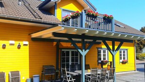 Un bâtiment jaune doté d’un balcon, d’une terrasse et d’un barbecue.