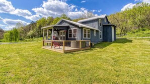 Une maison à deux étages avec un porche et une terrasse délimitée par une clôture.