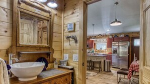 Un intérieur en bois agrémenté d’un grand miroir, d’un lavabo blanc et d’un meuble en bois.