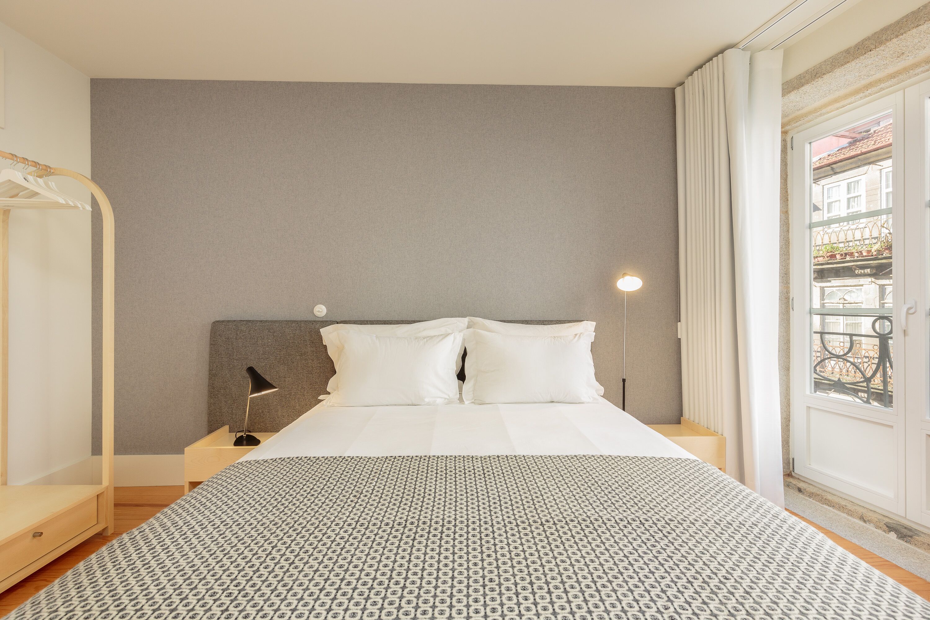 Ein Hotelzimmer mit Bett, Nachttisch, Lampe und Blick auf den Balkon.