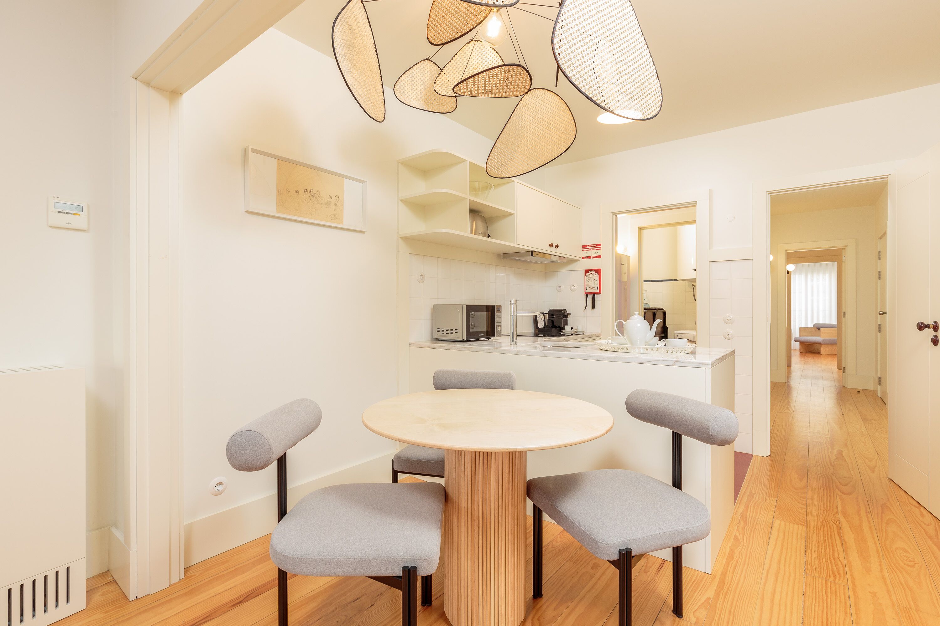 A modern kitchen with white cabinets, a microwave, and a coffee maker. There is a dining area with a round table and four chairs.