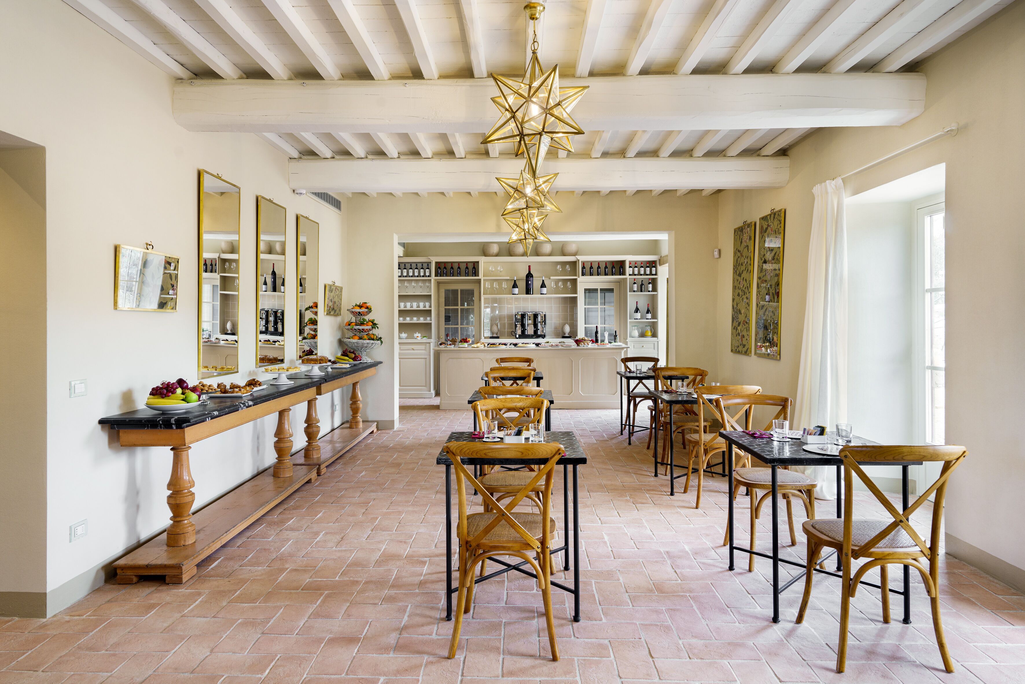A spacious dining area with wooden chairs and a long table, a kitchen with wine racks, and a ceiling with exposed beams.