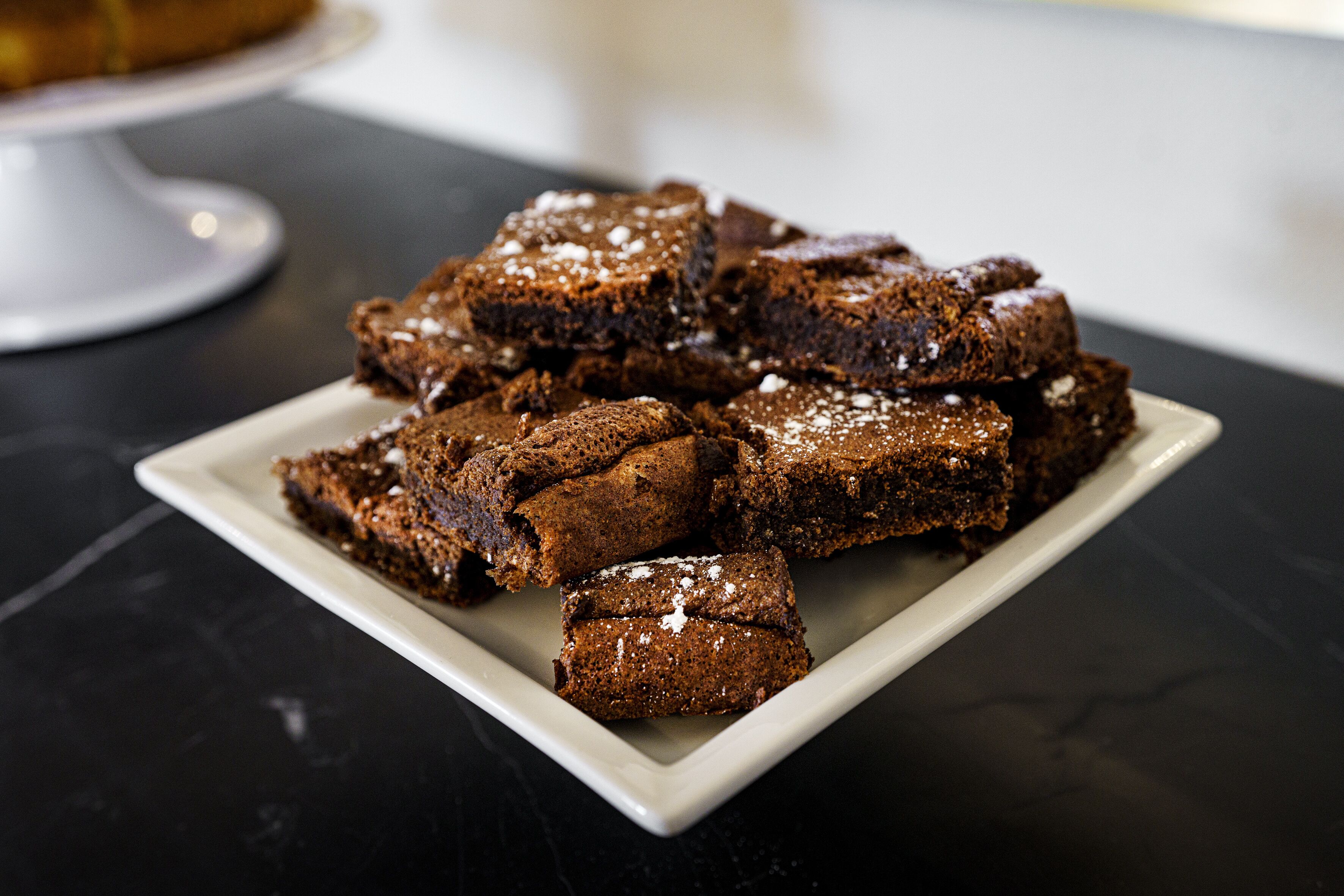 A plate of brownies on a dark surface.