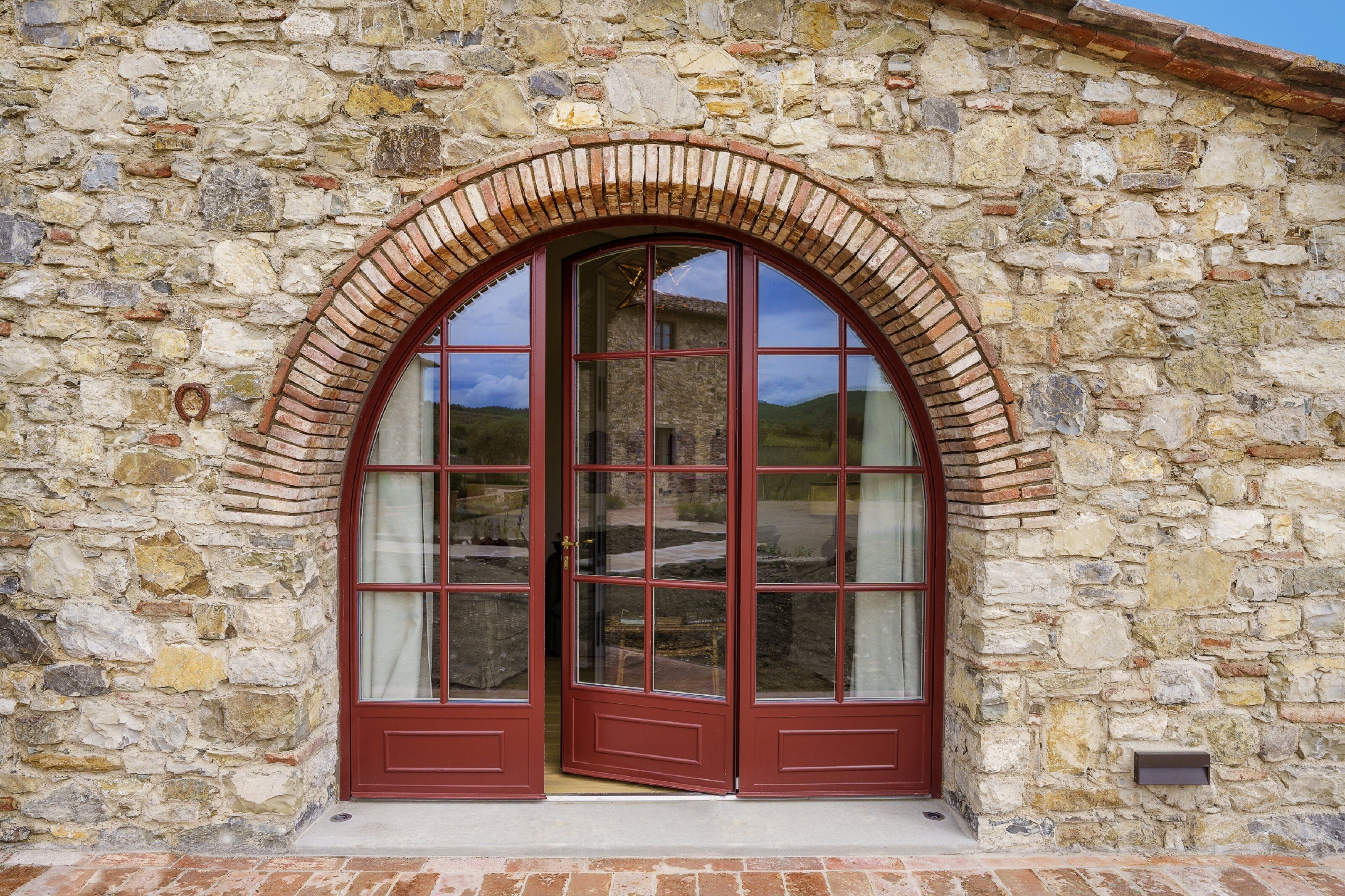 A stone building with a large arched window and a red door.