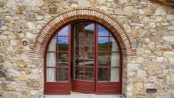 A stone building with a large arched window and a red door.