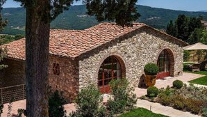 A stone building with a tiled roof, arched windows, and a well-maintained lawn. - La pietra del cabreo (Greve in Chianti)