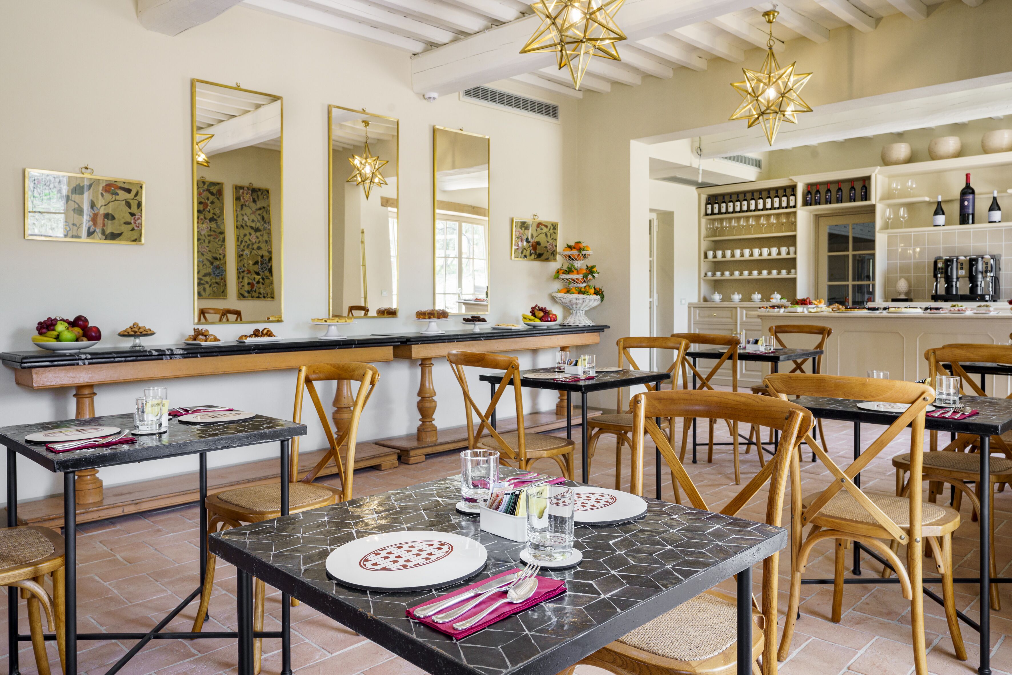 A dining area with tables set for meals, chairs, and a bar area with shelves of bottles and glasses.