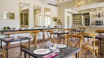 A dining area with tables set for meals, chairs, and a bar area with shelves of bottles and glasses.