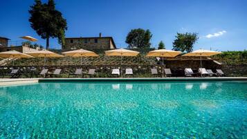 Relax by the serene pool surrounded by stone walls and comfortable sun loungers with umbrellas.