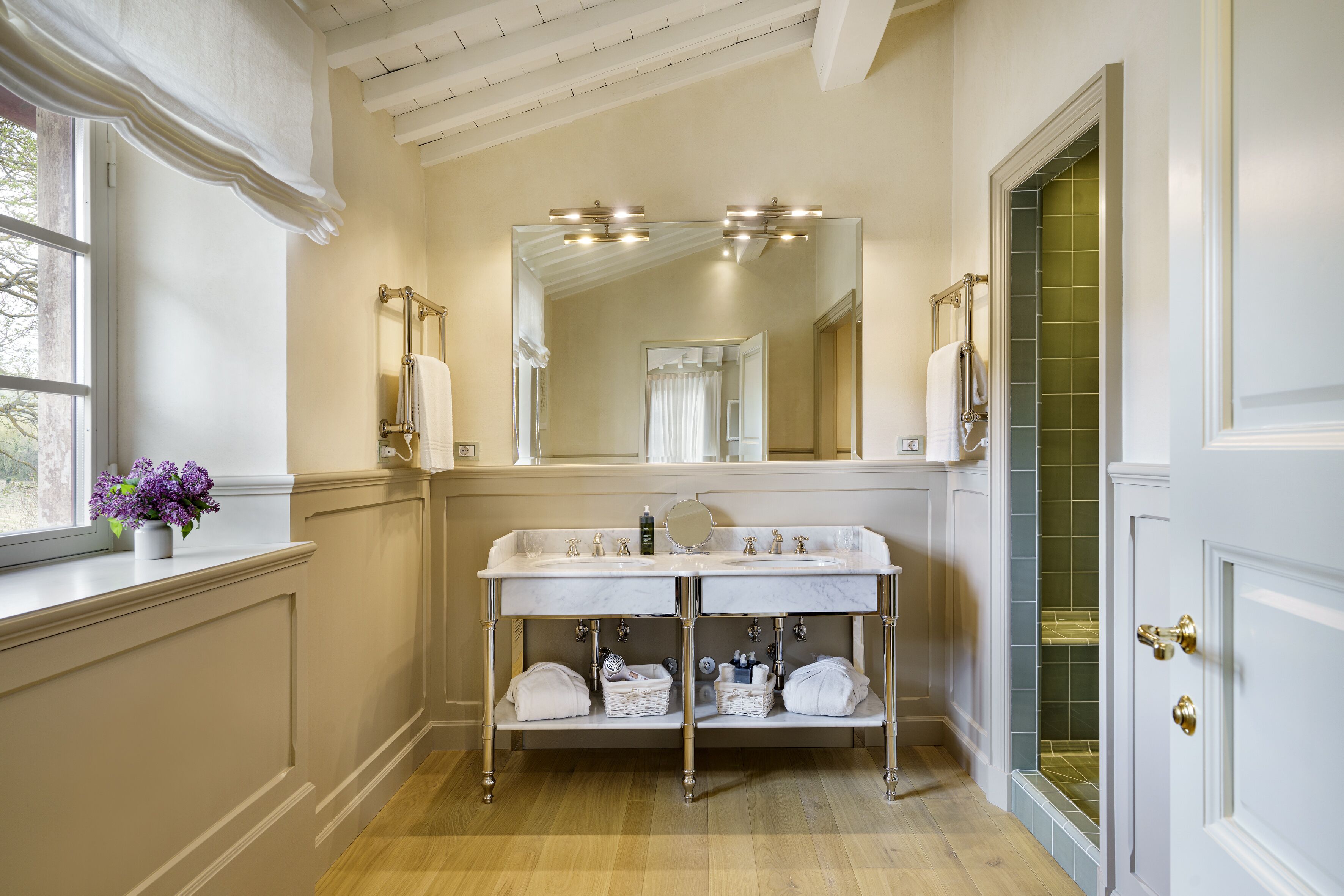 A bathroom with a double sink vanity, a large mirror, and a window with a view.