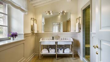 A bathroom with a double sink vanity, a large mirror, and a window with a view.