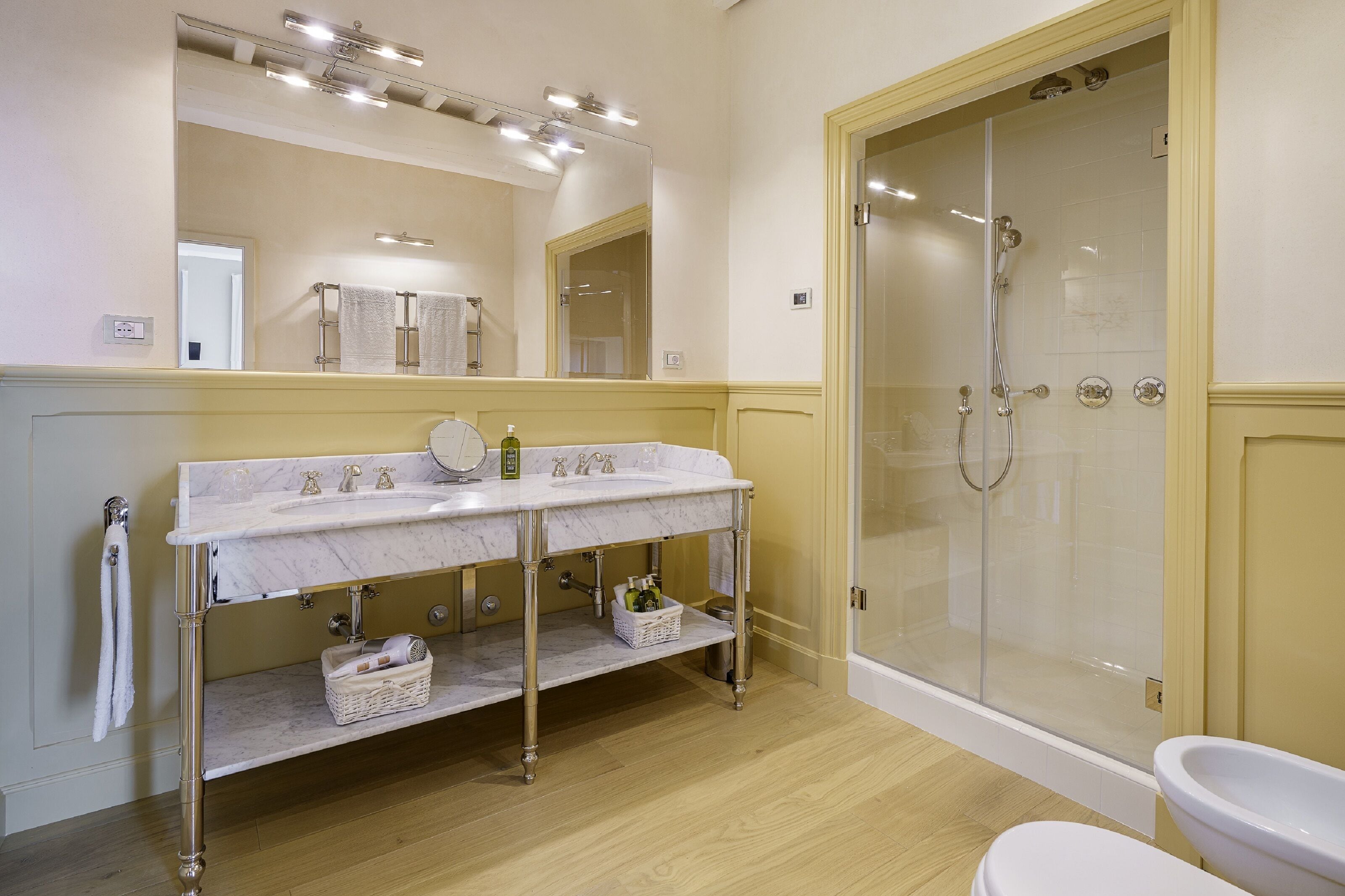 A bathroom with a marble sink, a glass-enclosed shower, and a white toilet.