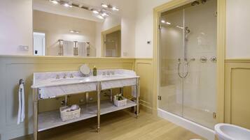 A bathroom with a marble sink, a glass-enclosed shower, and a white toilet.