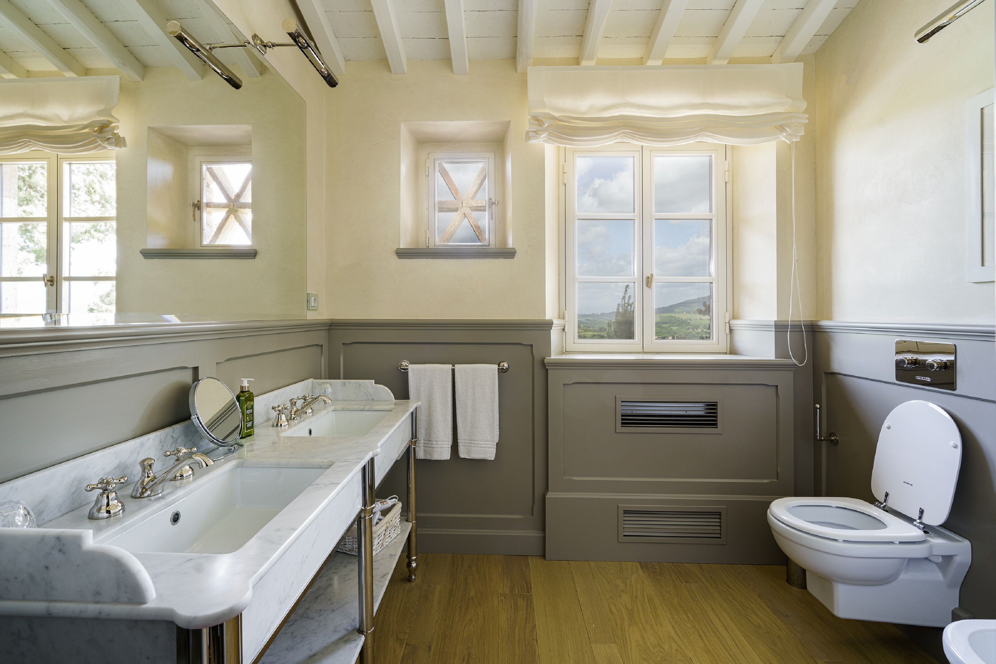 Une salle de bain dotée d’un grand meuble-lavabo, de toilettes et d’une fenêtre donnant sur l’extérieur.