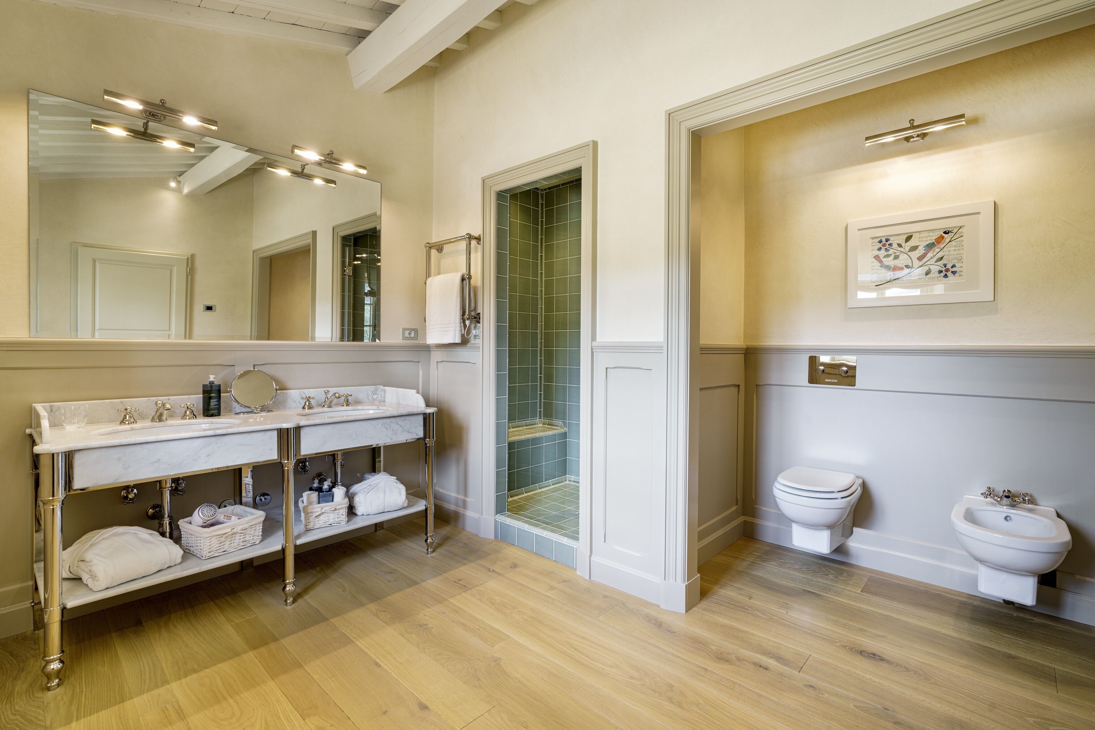 A bathroom with a double vanity, a large mirror, a toilet, and a bidet.