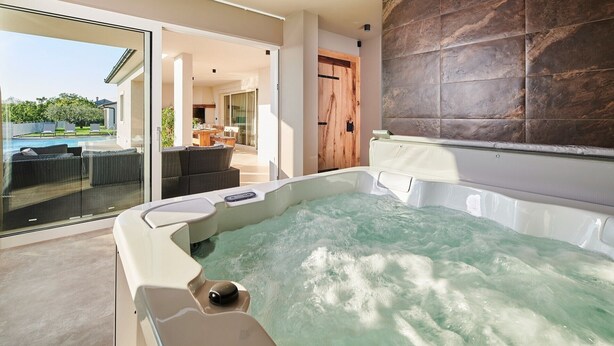 A modern spa area with a hot tub, glass doors leading to a poolside area, and a view of a garden. - Charming Villa Grgo with a pool and a mini wellness (Tinjan)