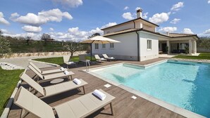 A modern house with a swimming pool, lounge chairs, and a covered patio area. - Charming Villa Grgo with a pool and a mini wellness (Tinjan)