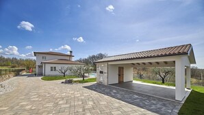 A modern house with a covered patio, a paved driveway, and a swimming pool. - Charming Villa Grgo with a pool and a mini wellness (Tinjan)