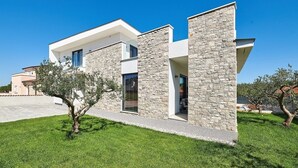 A modern two-story house with stone facade, large windows, and a well-maintained lawn. - Elegant Villa Dolcea with a swimming pool (Kaštel)