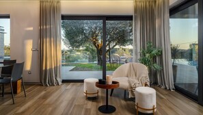 Relax in a spacious living room with a sofa, ottomans, and a coffee table, offering an outdoor area with a view of the surrounding landscape.