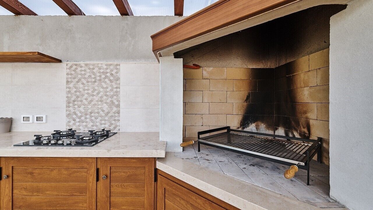 A kitchen with a gas stove, a grill, and a tiled backsplash.