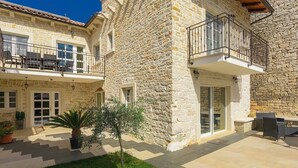 A stone building with a balcony, outdoor seating, and a small garden. - Beautifull Istrian Villa Patrick with a pool (Pazin)