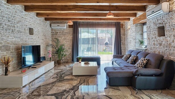 A living room with stone walls, a modern sofa, a flat-screen TV, and a marble floor. - Beautifull Istrian Villa Patrick with a pool (Pazin)