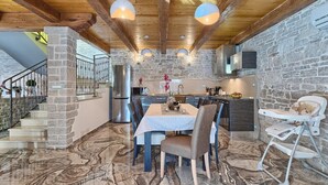 A modern kitchen with stone walls, a dining area with a marble floor, and a staircase with a stone pillar. - Beautifull Istrian Villa Patrick with a pool (Pazin)