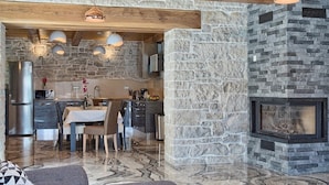 A modern kitchen with stone walls, a dining area with a table and chairs, and a fireplace. - Beautifull Istrian Villa Patrick with a pool (Pazin)