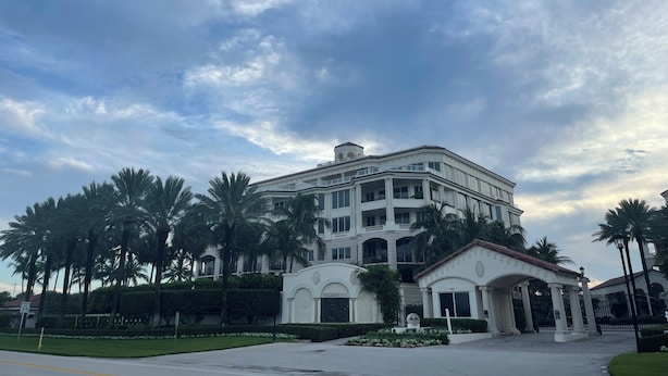 Un hotel grande de varios pisos con un estilo arquitectónico clásico, que cuenta con una entrada destacada con pórtico y un balcón con vista al jardín delantero.