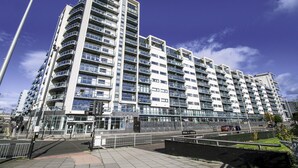 En moderne, flereetagers boligbygning med altaner, en lukket indgang og en belagt sti.