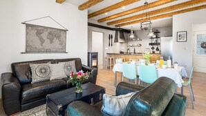Uma sala de estar moderna com um sofá de couro, um mapa-múndi e uma área de jantar com mesa e cadeiras.